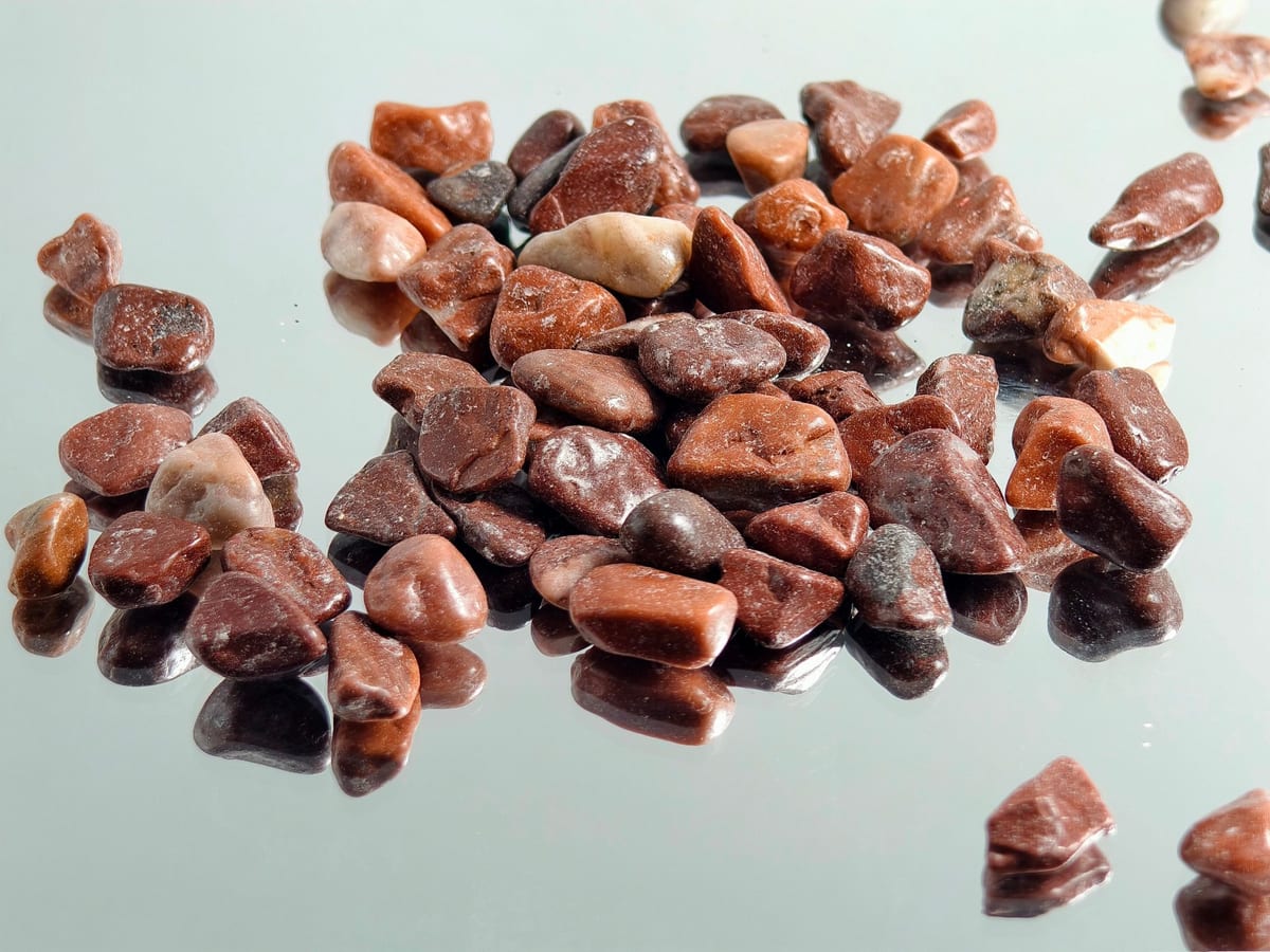 Red decorative gravel stockpile with coin size reference